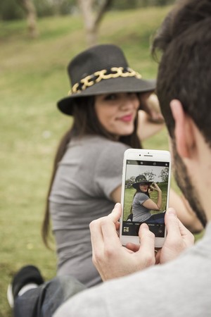 Man taking a photo of his girlfriend in a park