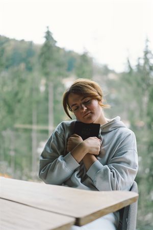 Woman holding a Bible while sitting in a forest